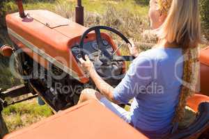 Rear view of woman driving tractor in olive farm