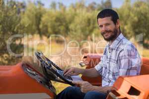 Portrait of happy man using laptop in tractor