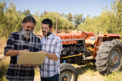 Friends using laptop in farm