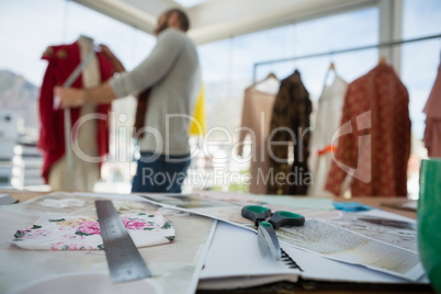 Equipment and designs on table with designer working in background