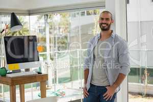 Portrait of smiling male designer leaning by window