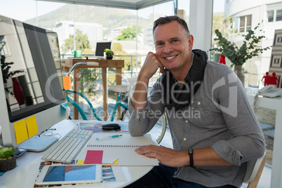 Portrait of smiling businessman sitting at desk