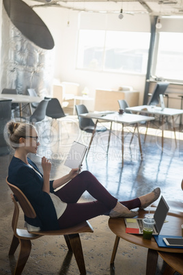 Businesswoman reading book while relaxing on chair at office