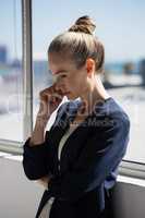 Thoughtful businesswoman looking lown while standing by window
