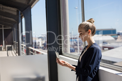 Businesswoman using digital tablet by window in office
