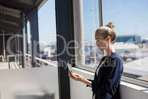 Businesswoman using digital tablet by window in office