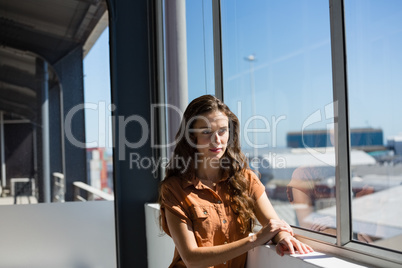 Thoughtful businesswoman looking away while standing by window