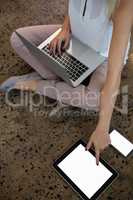 Low section of woman using laptop and tablet at office