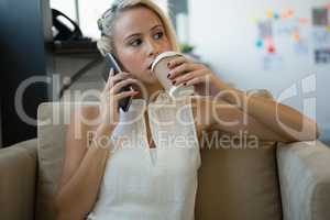 Businesswoman having coffee while talking on phone