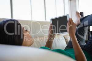 Businesswoman using tablet while lying down on sofa