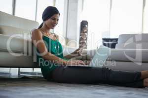 Young woman using laptop by sofa at office