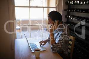 Man using laptop while talking on mobile phone