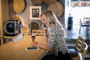 Beautiful woman talking on mobile phone at bar counter