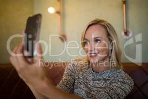 Beautiful woman taking selfie on mobile phone in bar