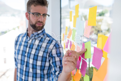 Male executive pointing at sticky note in office