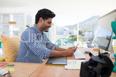 Graphic designer using mobile phone at desk