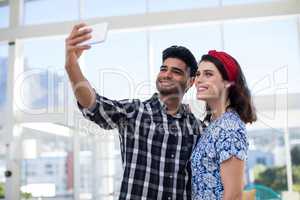 Couple taking selfie on mobile phone in the office