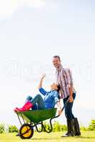 Man pushing woman sitting in wheelbarrow