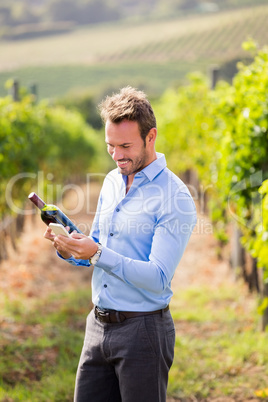 Smiling man with wine bottle using phone