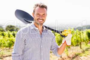 Portrait of man holding shovel at vineyard