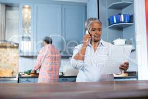 Woman reading document while standing in kitchen