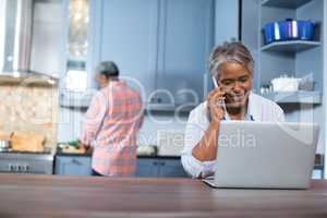 Woman talking on phone while using laptop