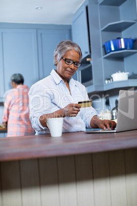 Smiling woman using credit card while doing online shopping