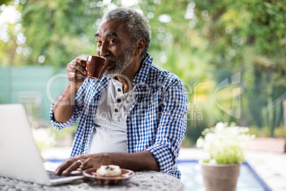 Senior man looking away while drinking coffee