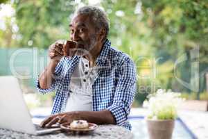 Senior man looking away while drinking coffee