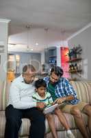 Boy using tablet while sitting with father and grandfather