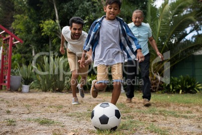 Happy family playing soccer in yard