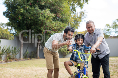 Boy learning bicycle with father and grandfather