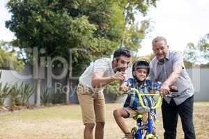 Boy learning bicycle with father and grandfather