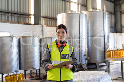 Portrait of female technician writing in clipboard