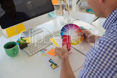 Designer holding color swatch while sitting at desk in office