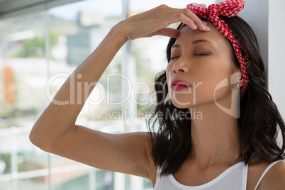 Tensed businesswoman with eyes closed leaning on wall