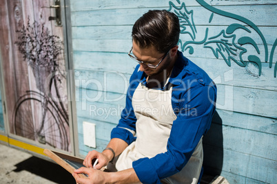 Owner writing menu while sitting by food truck