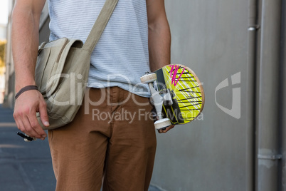 Midsection of man holding skateboard