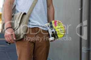 Midsection of man holding skateboard