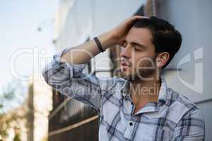 Tensed man sitting by wall