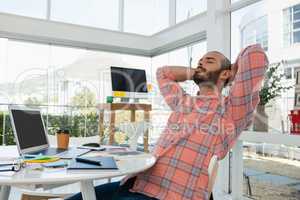 Designer with hands behind head relaxing at desk