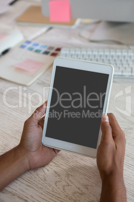 Cropped hands of man using tablet in office