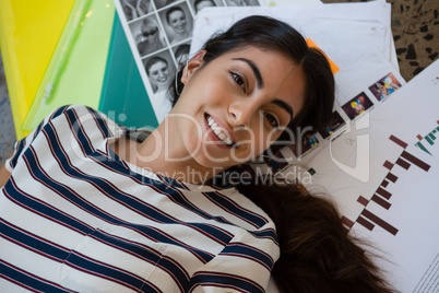 Portrait of woman lying on documents at office