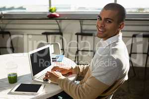 Portrait of man using laptop at office