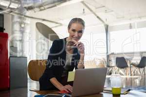 Portrait of smiling young woman using laptop in office