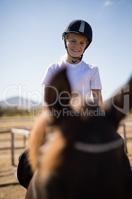 Smiling boy sitting on the horse in ranch