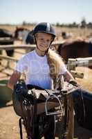 Smiling girl holding horse saddle