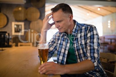 Worried man sitting at bar with glass of beer