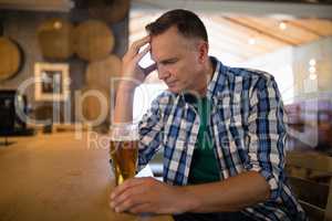 Worried man sitting at bar with glass of beer