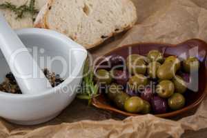 Close up of olives by spices in mortar pestle